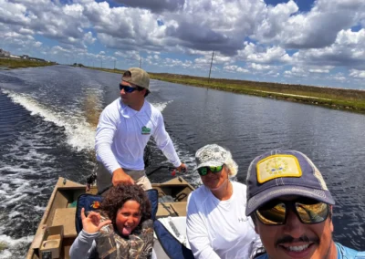 A group of people is riding in a boat on a sunny day, surrounded by calm waters and scattered clouds in the blue sky.